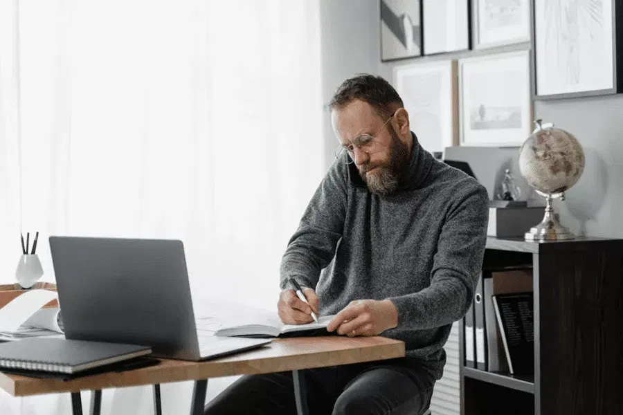 Man working at a desk on offshore strategies, surrounded by books and a globe, illustrating asset protection methods.
