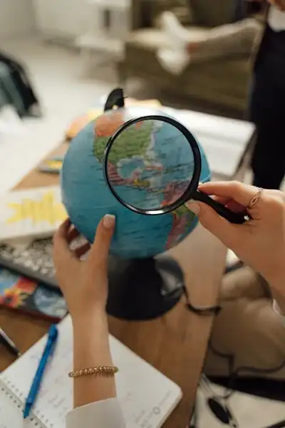 Person examines globe with magnifying glass, symbolizing comparing offshore trust jurisdictions for asset protection.